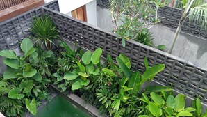 Un bassin rectangulaire, entouré d’une végétation luxuriante et délimité par une clôture moderne.