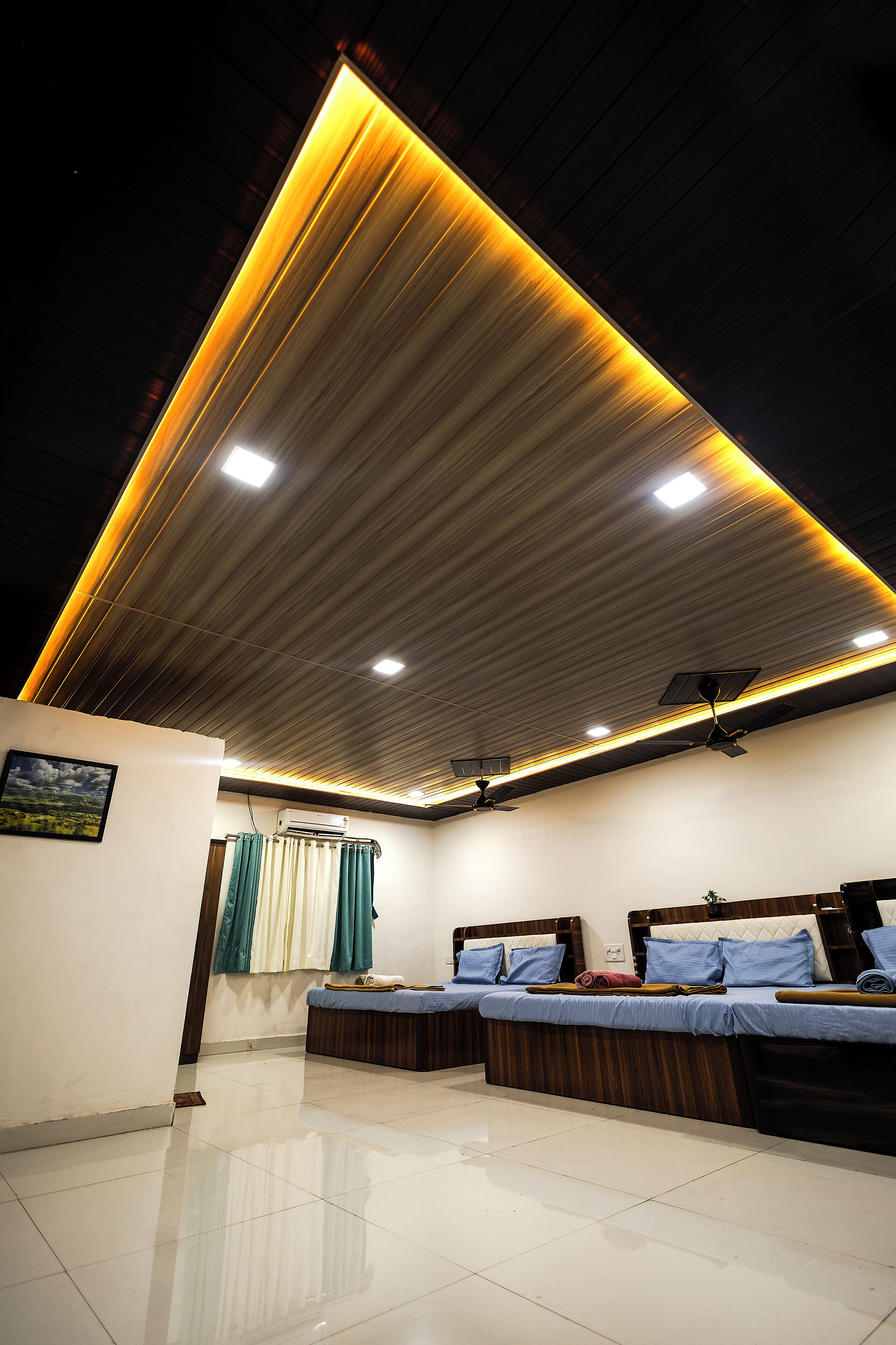 A modern room with a sloped ceiling, two beds with headboards, a ceiling fan, and a wall-mounted air conditioner.