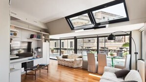 Una sala de estar moderna con un tragaluz grande, un comedor y vistas a la ciudad.