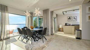 Un espace repas moderne avec une table et des chaises, un panier de fruits et une vue sur lâeau.