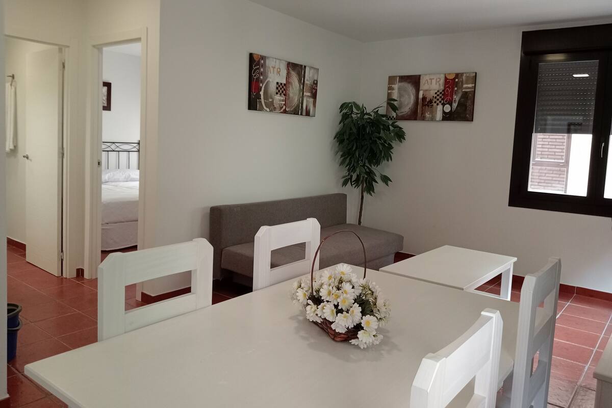 Een hotelkamer met een bed, een bank, een eettafel met stoelen en twee kunstwerken aan de muur.