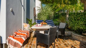 Eine Terrasse im Freien mit Tisch, Stühlen und einer Bank.