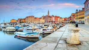 Un port de plaisance avec des bateaux amarrés, une balustrade en pierre et, au fond, des bâtiments aux couleurs vives.