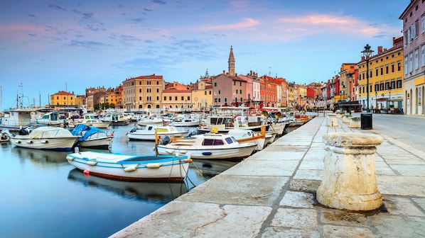 A marina with boats docked, a stone balustrade, and colorful buildings in the background.