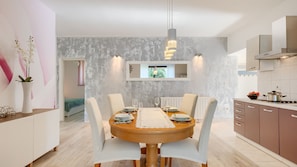 A modern dining area with a round table, white chairs, and a wooden floor.