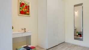 A bathroom with a white vanity, a mirror, and a framed painting above the sink.
