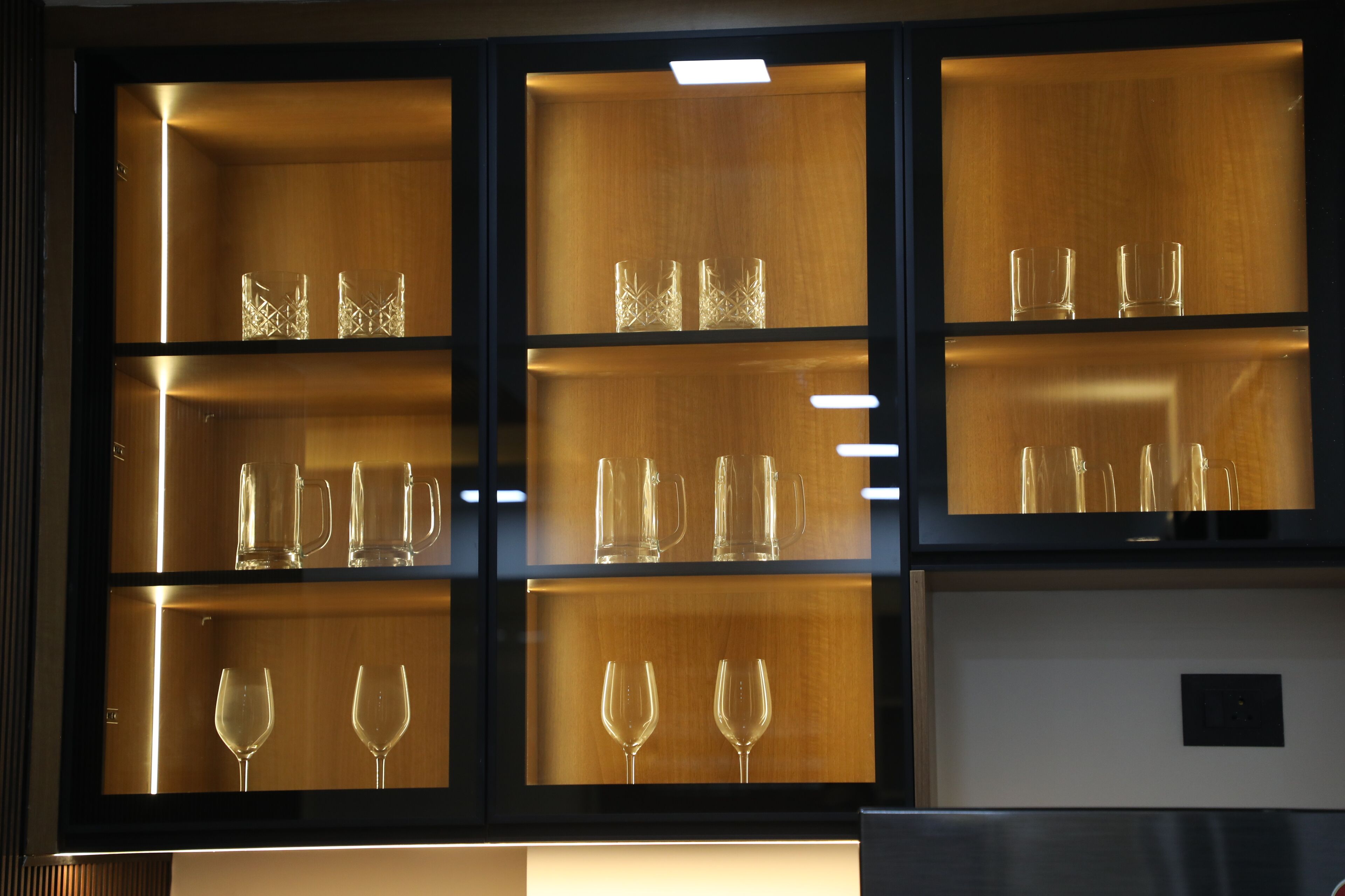 Una colección de cristalería en un gabinete de madera bien iluminado.