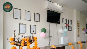 A reception area with framed certificates, a mounted television, and a decorative plant arrangement. - Ranthambore Hotel and Restaurant (Jaipur)