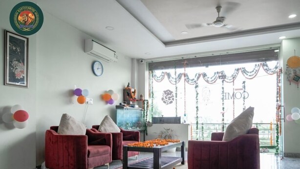 A room with red sofas, a coffee table, and a decorative window view. - Ranthambore Hotel and Restaurant (Jaipur)