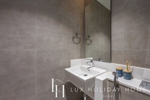 A modern bathroom with a large mirror, a sink, and a shower.