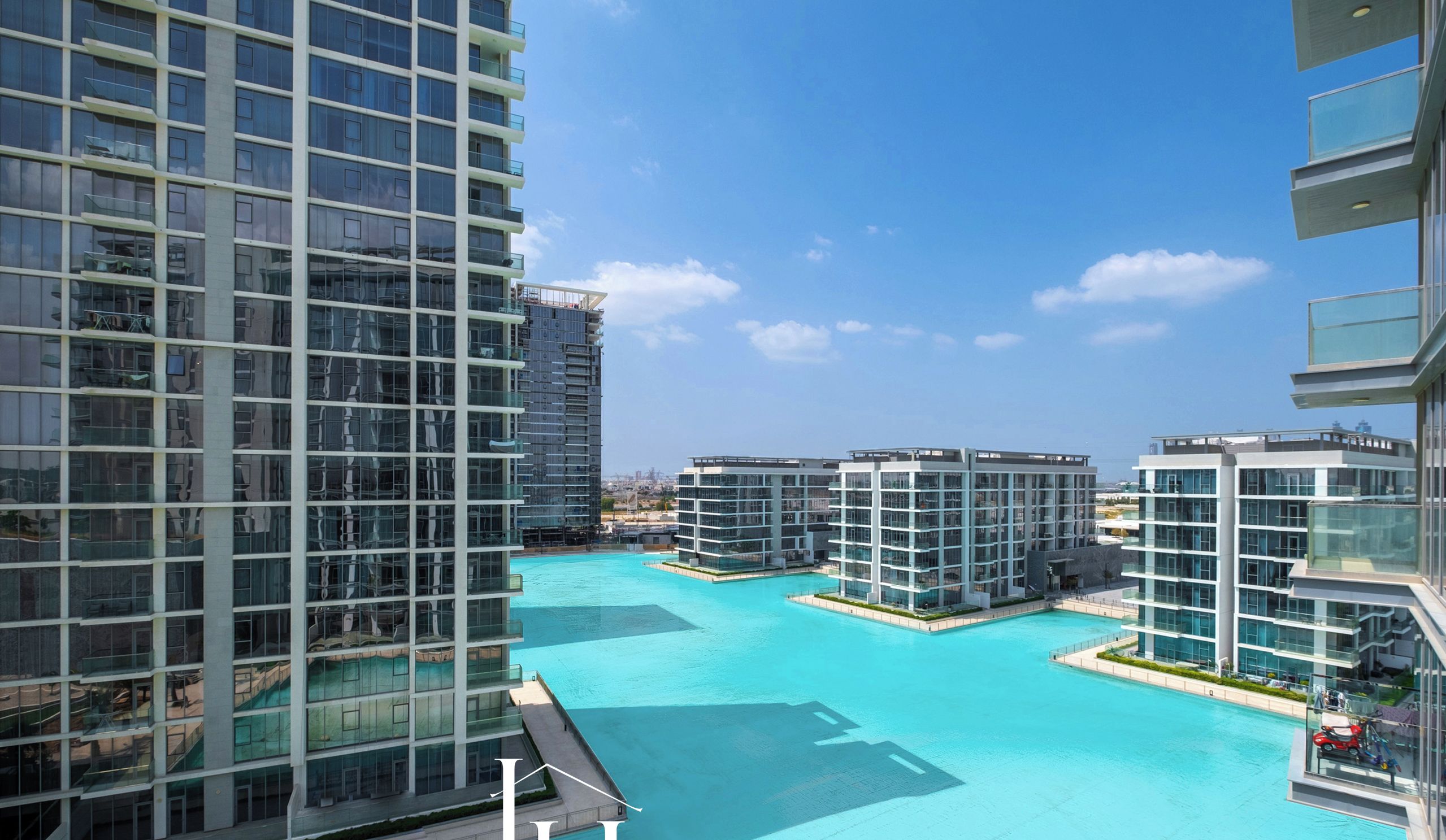 A modern high-rise building with a large swimming pool surrounded by other high-rise buildings.