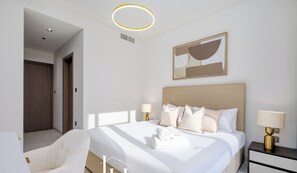A modern hotel room with a large bed, two bedside tables with lamps, a chair, and a painting on the wall.