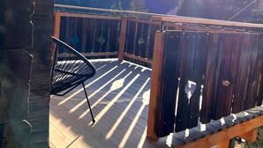 A wooden deck with a chair, overlooking a mountainous landscape.