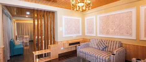 A modern living room with a wooden ceiling, a striped sofa, a glass coffee table, and a bench.