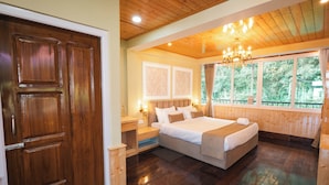 Una habitación con paneles de madera, una cama grande, una mesita de noche y una ventana con cortinas.