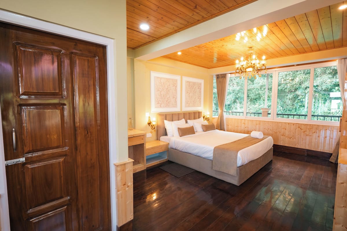A wooden-paneled room with a large bed, a nightstand, and a window with curtains.