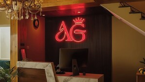 Una recepción con un letrero de neón, un candelabro y una escalera.