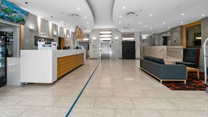 A modern hotel lobby with a reception desk, seating area, and a view of the elevator. - 2-Bed City Retreat with Gym and Pool Access (Adelaide)
