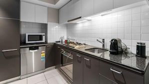 A modern kitchen with stainless steel appliances, a microwave, a coffee maker, and a kettle. - 2-Bed City Retreat with Gym and Pool Access (Adelaide)