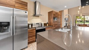 Une cuisine moderne dotée d’appareils électroménagers en acier inoxydable, d’un four encastré et d’un grand îlot central avec un évier.
