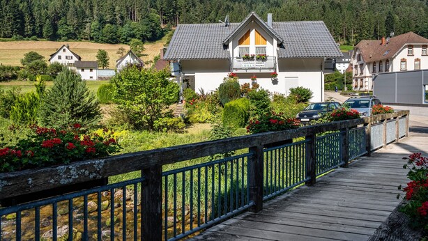 Un hotel con balcón, rodeado de vegetación y una terraza de madera.