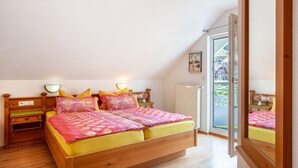 Un dormitorio con cama de madera, mesita de noche, ventana con vistas y puerta que da a un espacio exterior.