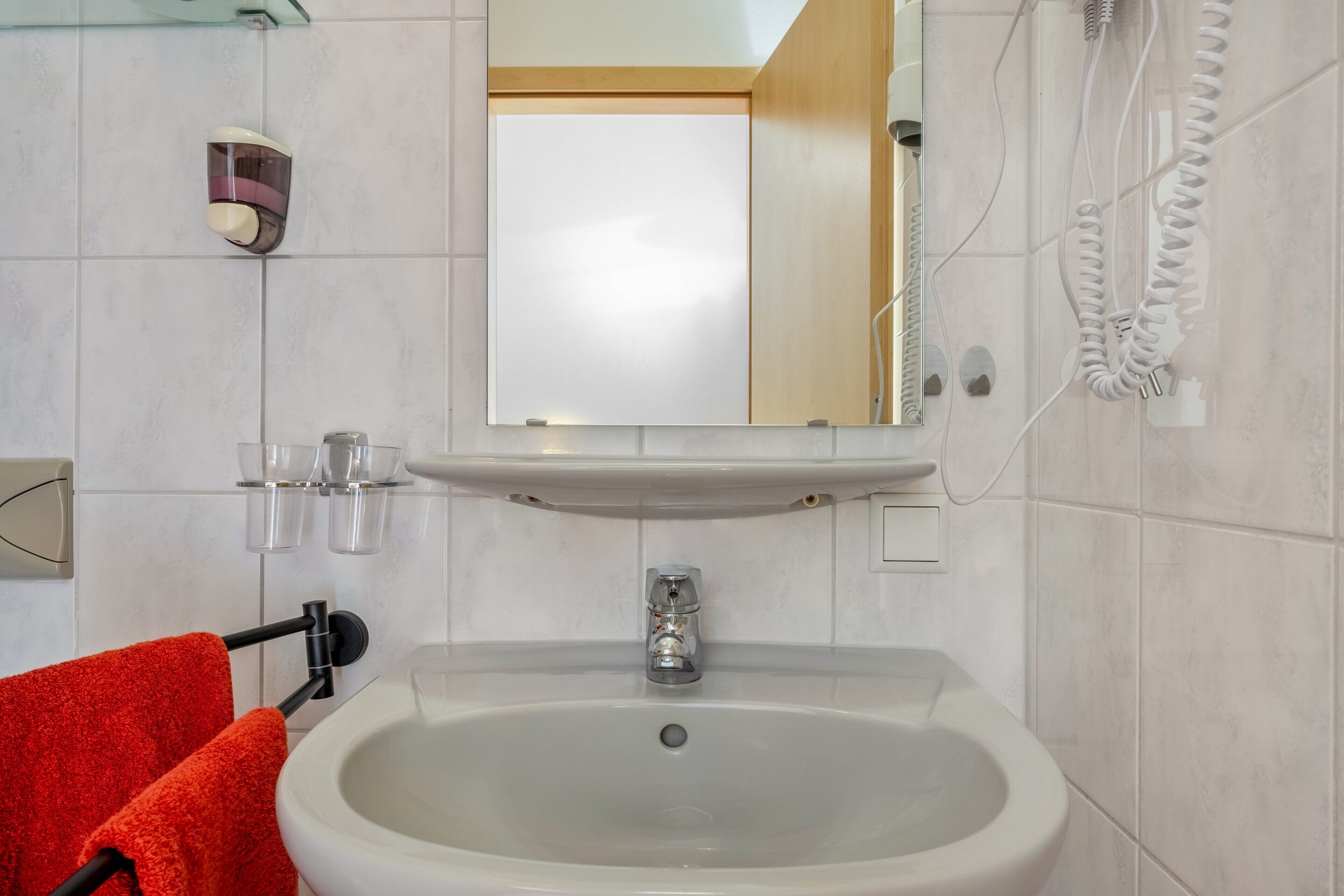 A bathroom with a sink, mirror, and towel rack.
