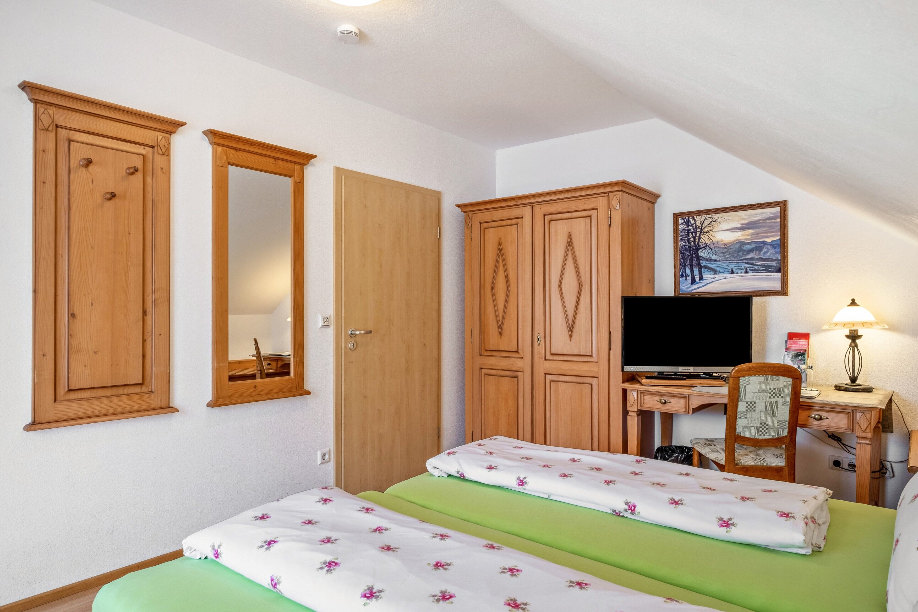 Une chambre à coucher comprenant un lit, un bureau, une chaise et des armoires en bois.