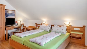 Ein Schlafzimmer mit zwei Betten, einem Schreibtisch, einem Stuhl, einem Fernseher und einem Bild an der Wand.