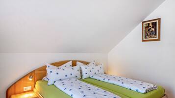 Une pièce comprenant un lit, une table de chevet, un tableau accroché au mur et un plafond en pente.