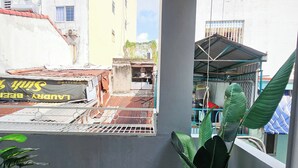 A balcony with a view of buildings, a potted plant, and a tiled floor. - H2T Hotel - Center Bui Vien (Ho Chi Minh City)