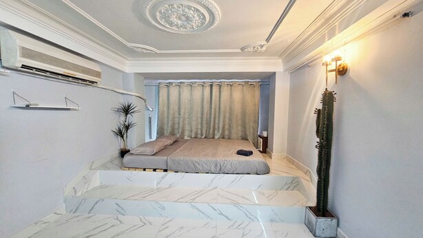A bedroom with a bed, a potted plant, a nightstand, and a wall-mounted air conditioner. - H2T Hotel - Center Bui Vien (Ho Chi Minh City)
