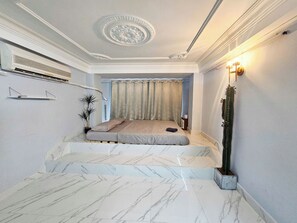 A bedroom with a bed, a potted plant, a nightstand, and a wall-mounted air conditioner. - H2T Hotel - Center Bui Vien (Ho Chi Minh City)