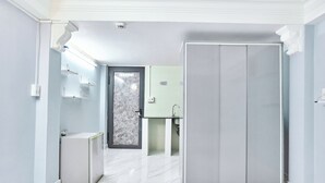 A modern hotel room with a marble floor, a wardrobe, a small refrigerator, a sink, and a door leading to another room. - H2T Hotel - Center Bui Vien (Ho Chi Minh City)
