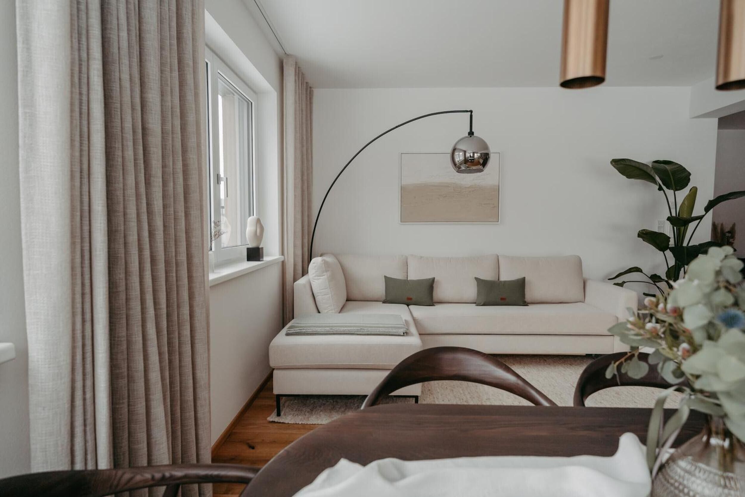 Una sala de estar moderna con un sofá, una mesa de comedor y una lámpara.