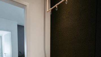 Un sillón blanco en una habitación con una pared oscura, una mesa de cristal con una bebida, y una puerta que da a otra habitación.