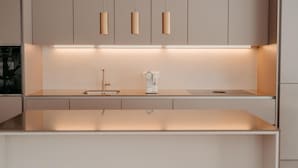 A modern kitchen with a central island, pendant lights, and a coffee machine. - Fjell Apart Schladming-Dachstein (Gröbming)