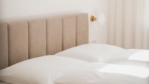 A bed with a headboard, a wall-mounted light fixture, and a window with curtains. - Fjell Apart Schladming-Dachstein (Gröbming)