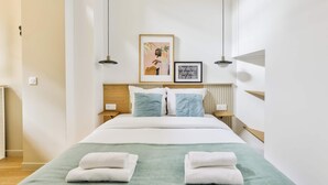Une chambre d’hôtel moderne avec un grand lit, deux tables de chevet, une tête de lit et un tableau encadré au mur.