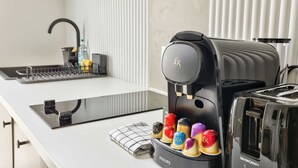 Une cuisine équipée d’une machine à café, d’un grille-pain et d’un assortiment de capsules de café aux couleurs vives.