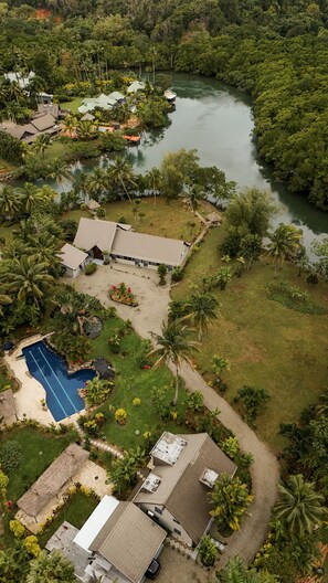 An aerial view of a residential area with houses, a swimming pool, and a river.