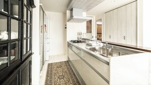 Una cocina moderna con estufa integrada, pileta de acero inoxidable y muebles oscuros.