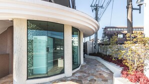 Un edificio moderno con amplios ventanales, fachada curva y área de entrada empedrada con piedra.