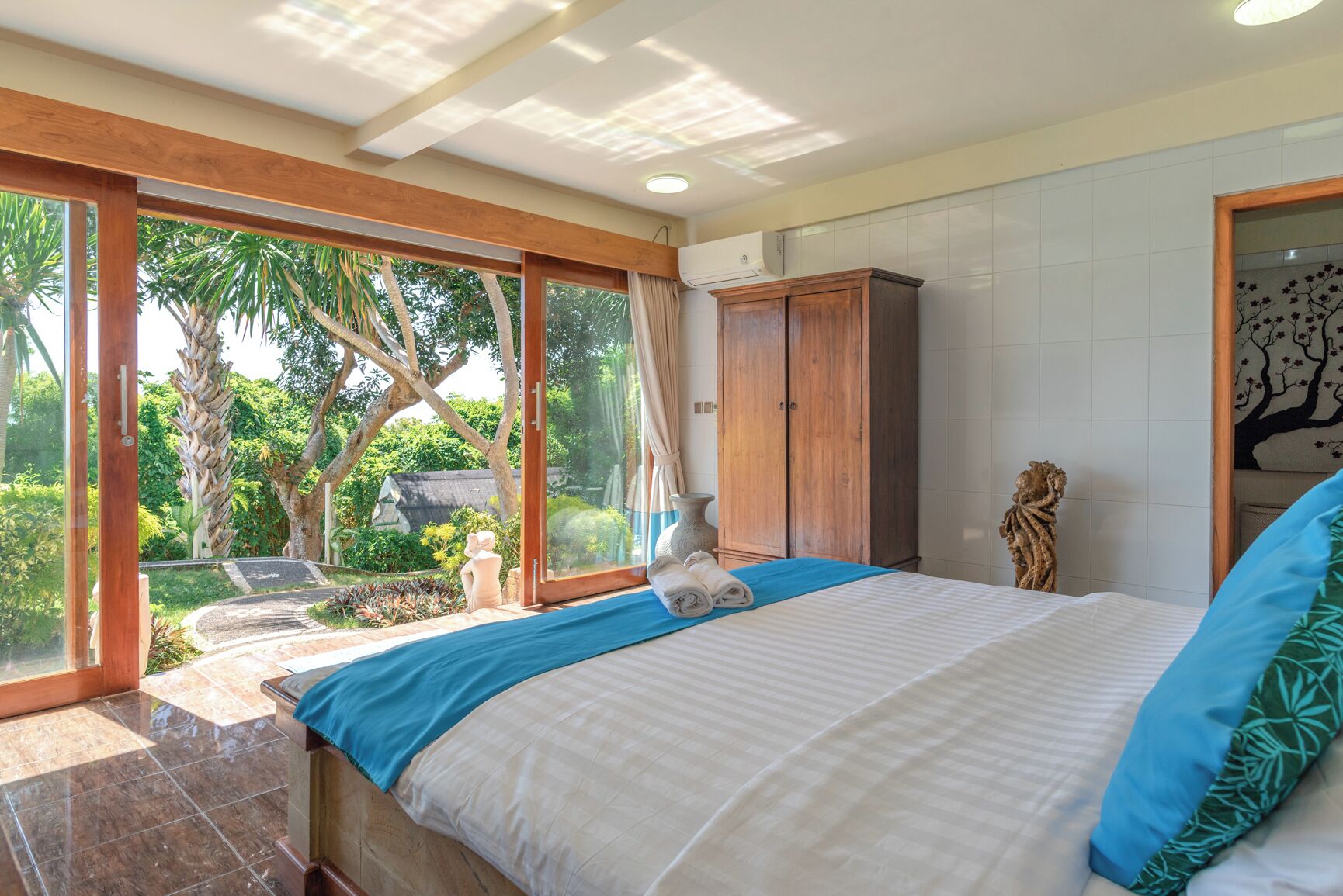 Un dormitorio con una cama grande, un armario y vistas a un jardín a través de puertas de vidrio.
