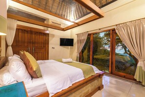 A spacious bedroom with a large bed, wooden headboard, and a television on the wall. - Bougainville Hill Villa (Sukasada)