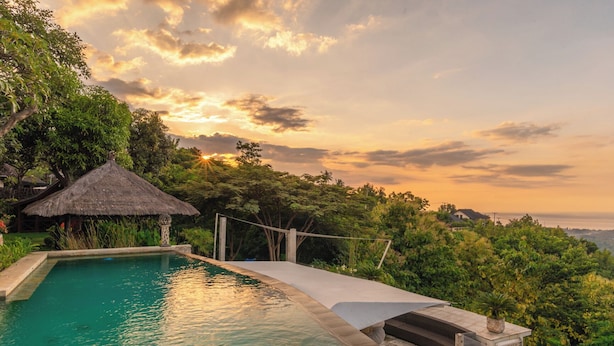 A swimming pool with a thatched-roof hut, surrounded by lush greenery and overlooking a scenic landscape. - Bougainville Hill Villa (Sukasada)