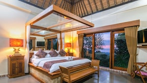 A spacious bedroom with a four-poster bed, large windows, and a view of the outdoors. - Bougainville Hill Villa (Sukasada)