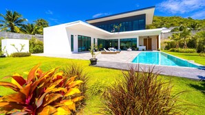 Ein modernes, zweistöckiges Haus mit Schwimmbad, großen Glasfenstern und einem gepflegten Garten.