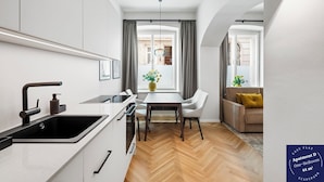 Een moderne keuken met een spoelbak, fornuis en een eethoek. Er is een raam met gordijnen, een bank en een tafel met stoelen.