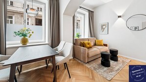 Een moderne woonkamer met een bank, een eettafel en een groot raam.